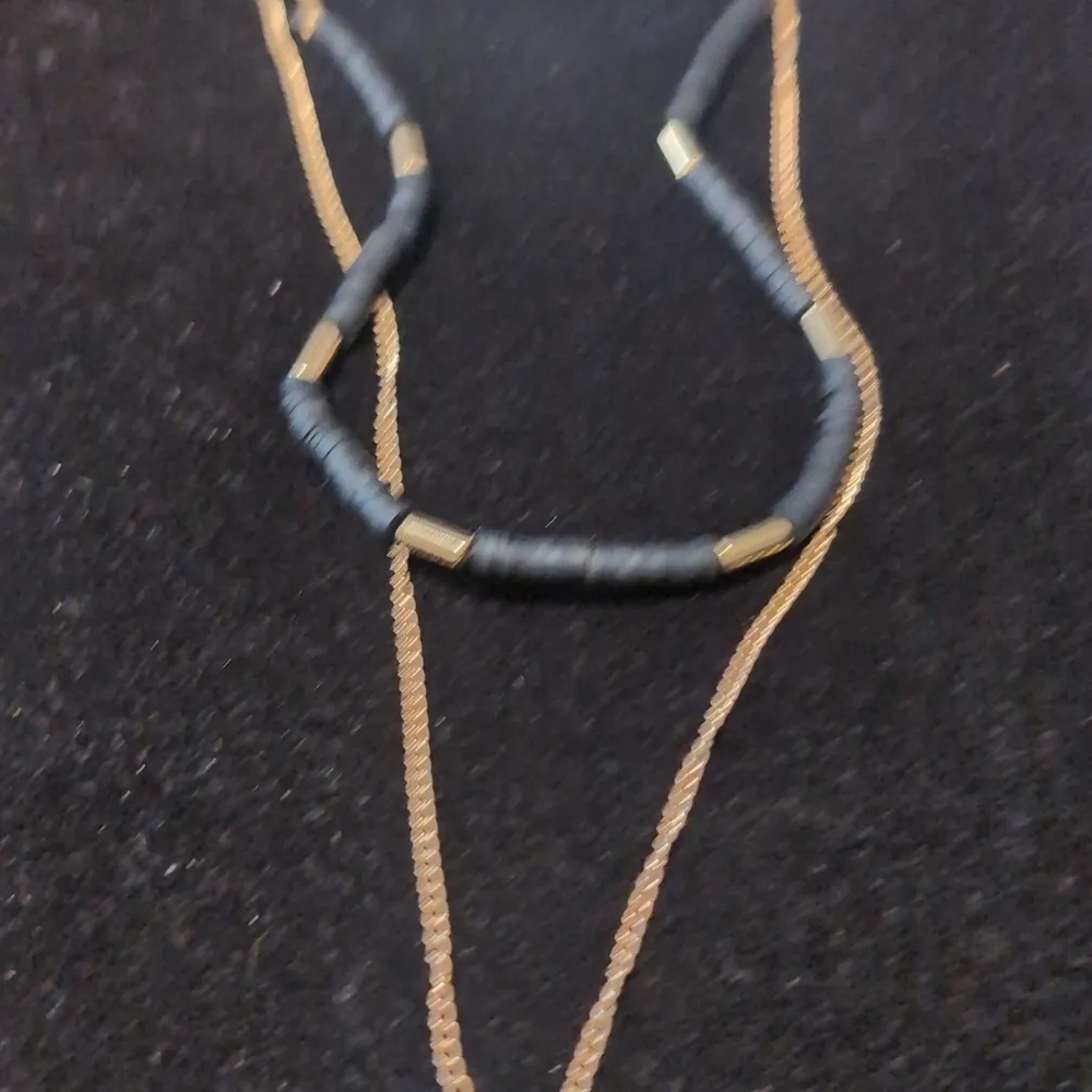 gold toned layered necklace featuring Black beaded strands and an evil eye charm